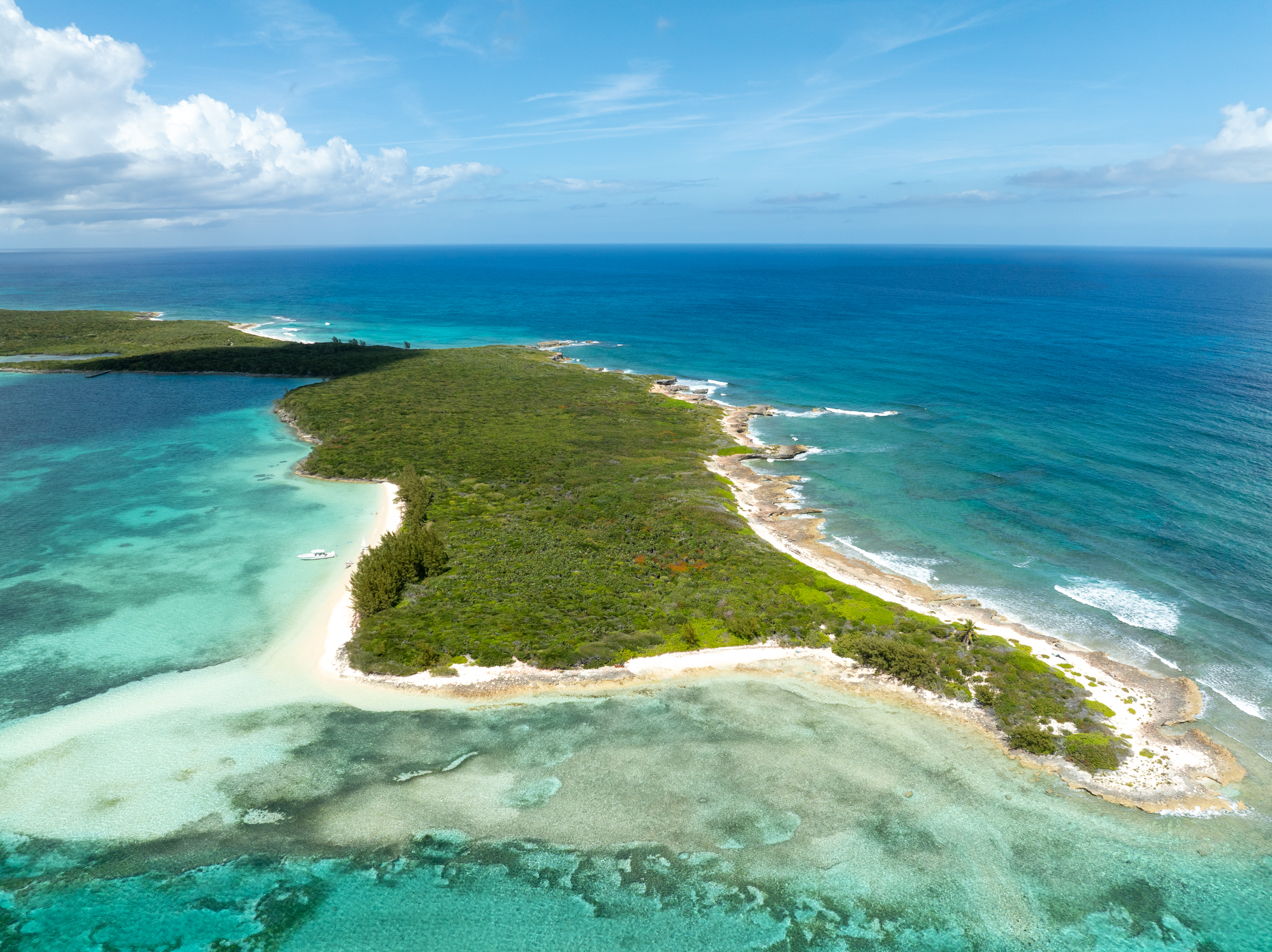 Aerial view of a remote private Bahamian island ringed by turquoise reefs