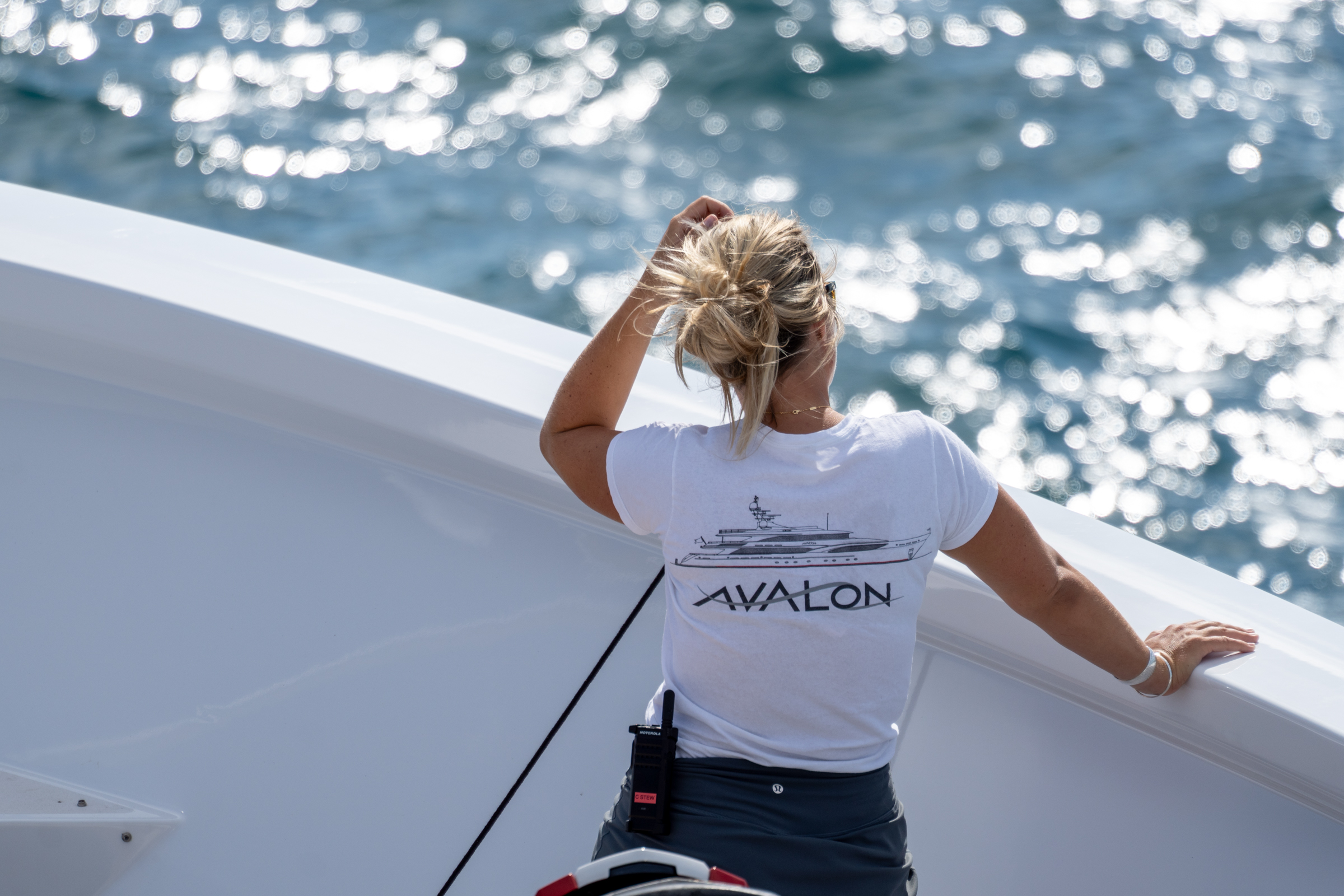 Avalon crew member in branded shirt looking out from the bow