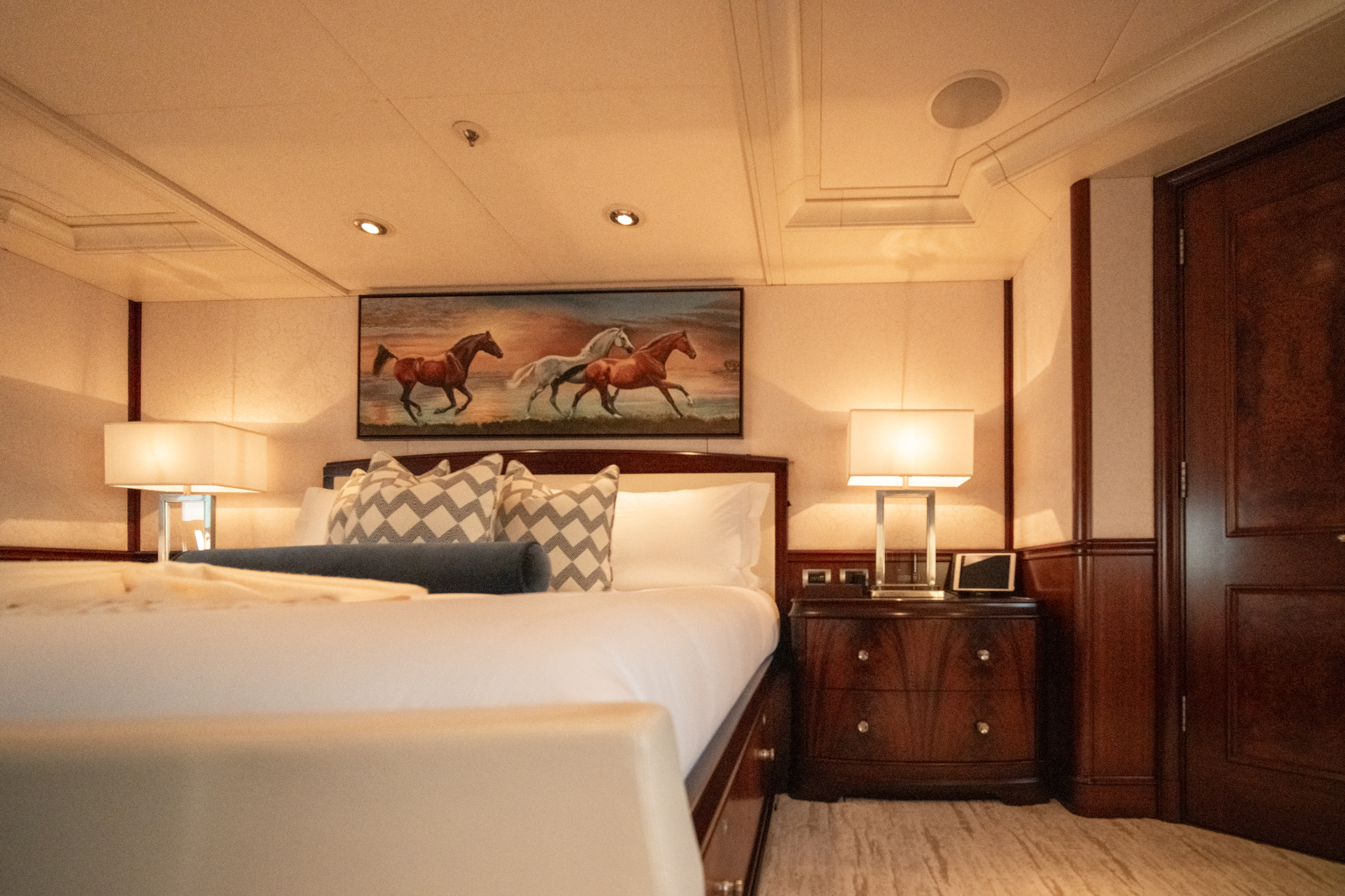 Guest stateroom aboard Motor Yacht Avalon with framed equestrian art and mahogany joinery