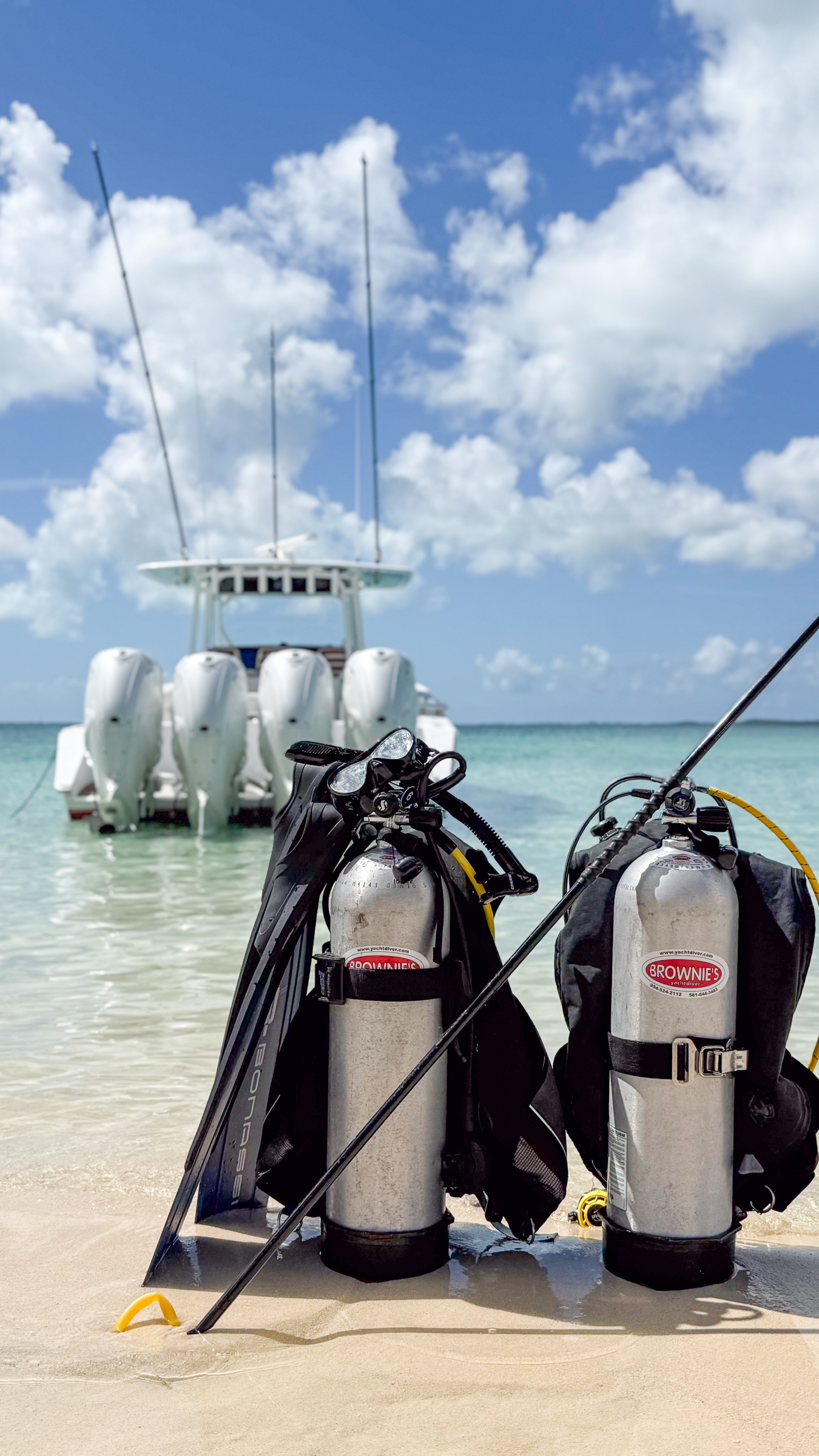 Scuba tanks and fins staged on a Bahamian beach beside Avalon's tender